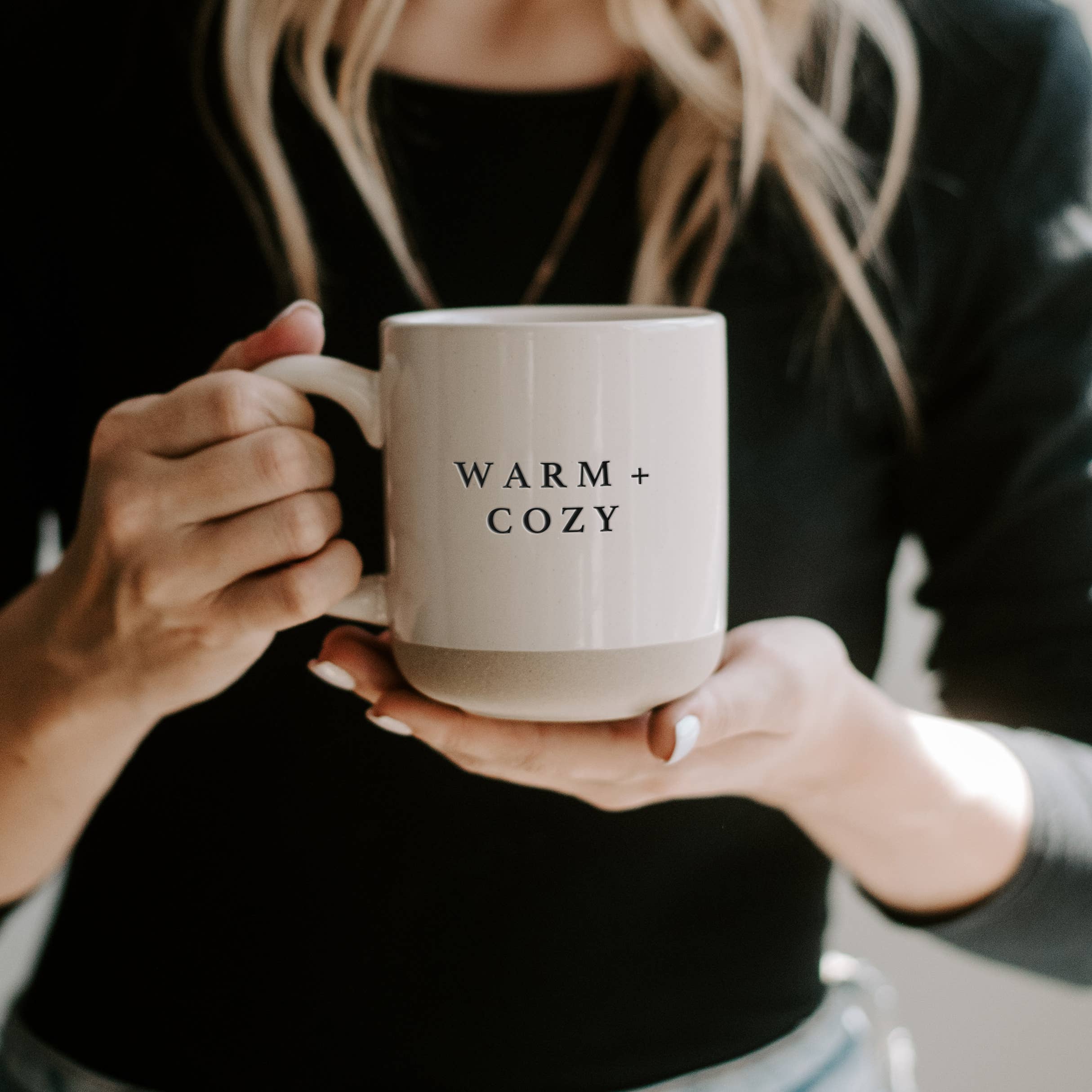 Person holding a mug with 'WARM + COZY' text