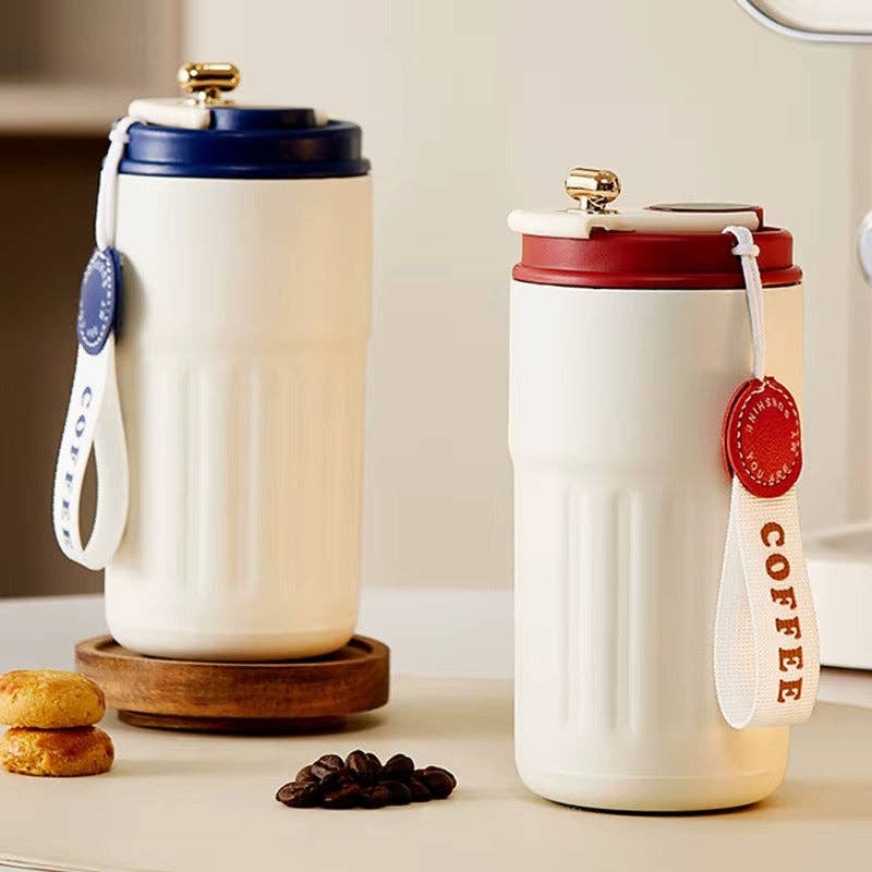 Two white travel mugs with colorful lids and tags on a kitchen counter.