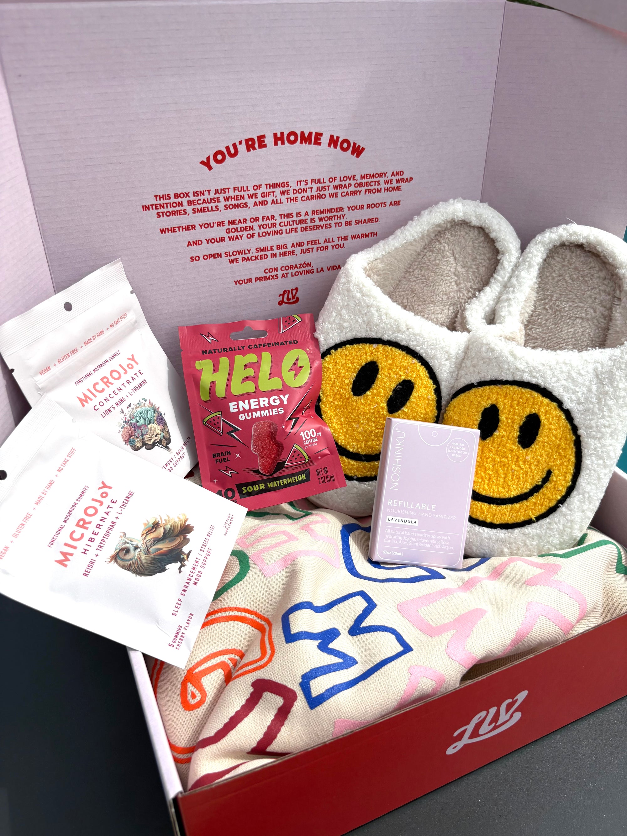 Box with slippers, snacks, and a towel with smiley face design.