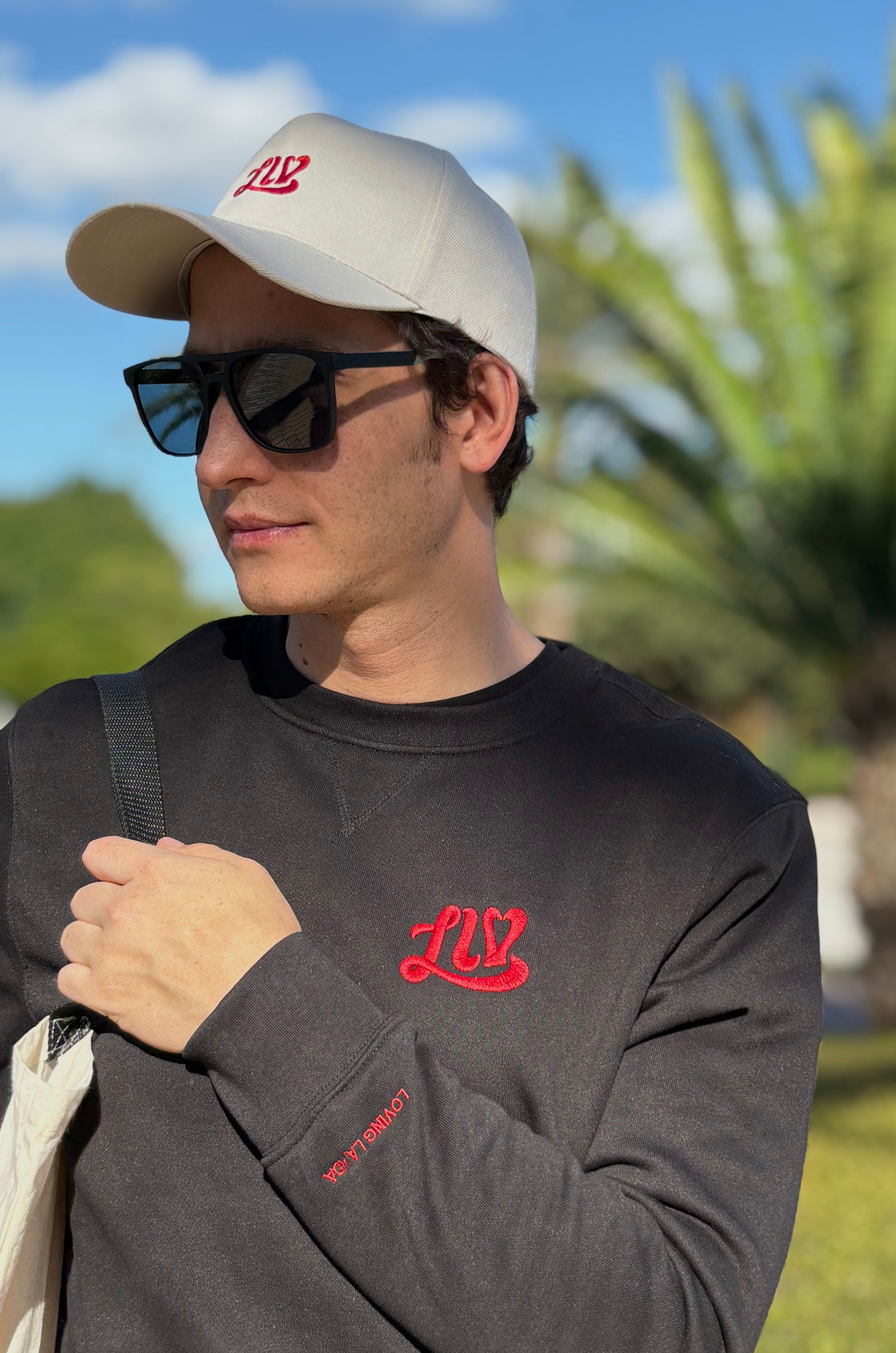 Man wearing a cap and sunglasses with 'LIV' branding outdoors