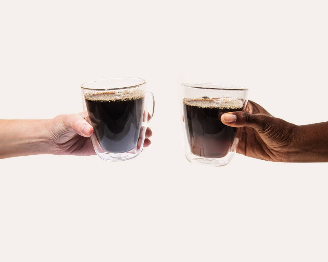 Two hands holding glasses of black coffee against a white background