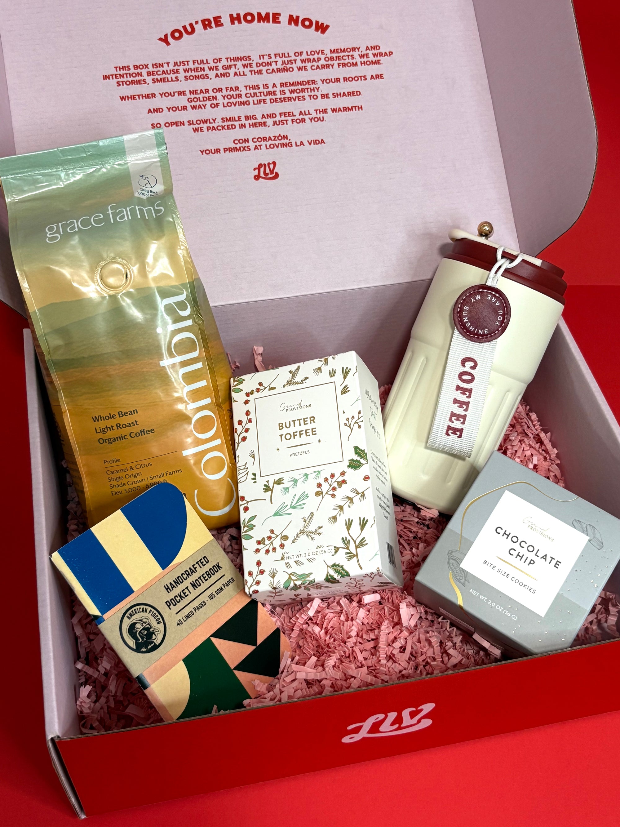 Gift box with coffee-themed items including a coffee bag, mug, and chocolate bar on a red background.